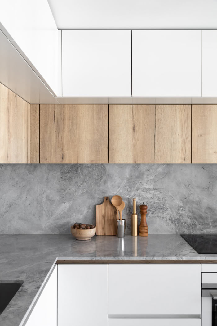 Détail de l'agencement d'une cuisine sur mesure mêlant bois clair et façades blanches, conçu par un expert en rénovation à Metz.