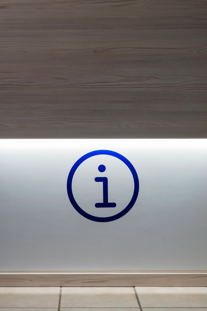 Détail signalétique lumineuse "Information" sur comptoir en bois, aménagement de bureaux administratifs en Moselle Est. 