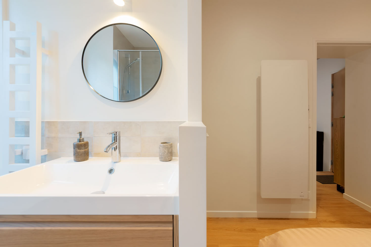 Vue d'ensemble de la salle de douche rénovée avec radiateur sèche-serviette et rangements intégrés.