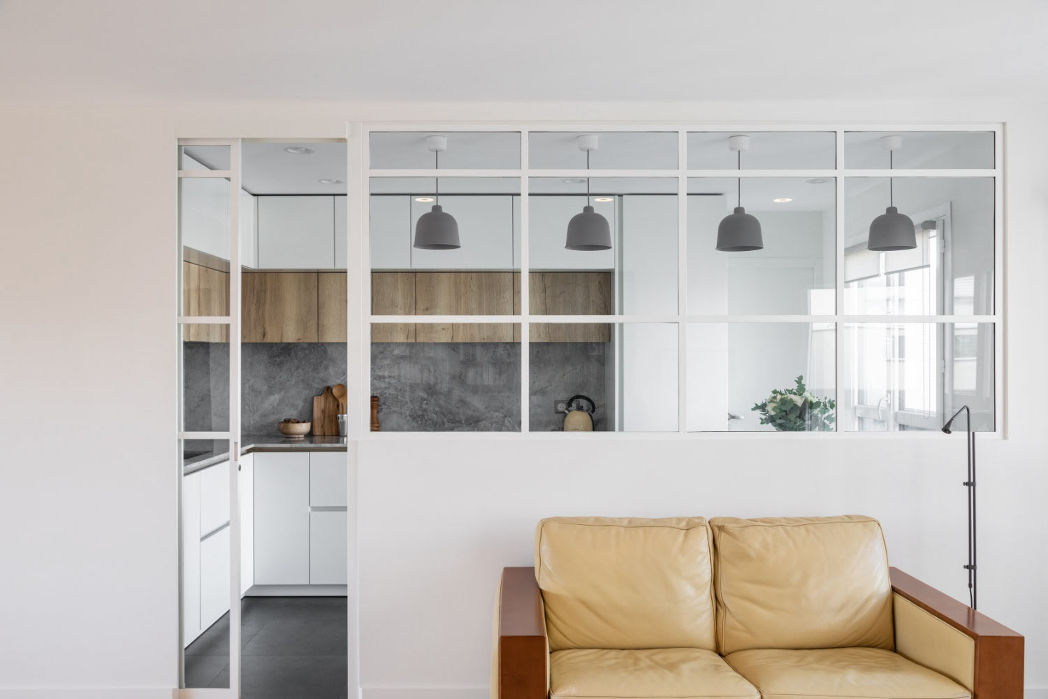 Vue d'ensemble d'un séjour rénové par Guillaume Steffanus, architecte d'intérieur à Metz, montrant la verrière et l'ouverture sur la cuisine.