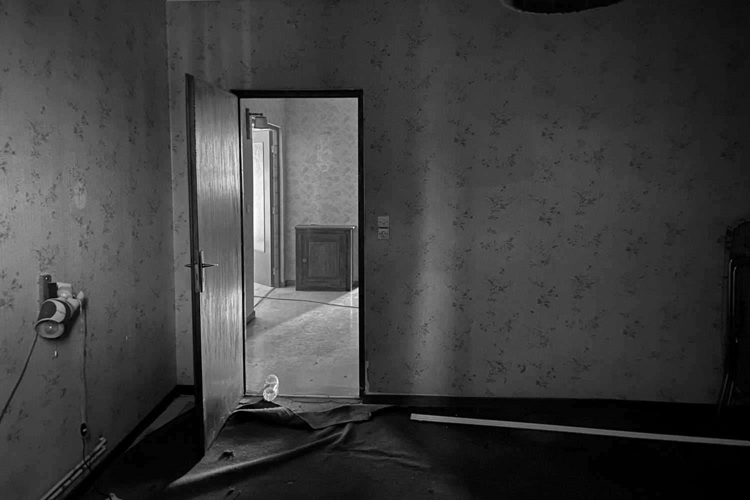 Chambre ancienne avec papier peint à fleurs et moquette usée avant rénovation complète en Moselle Est.