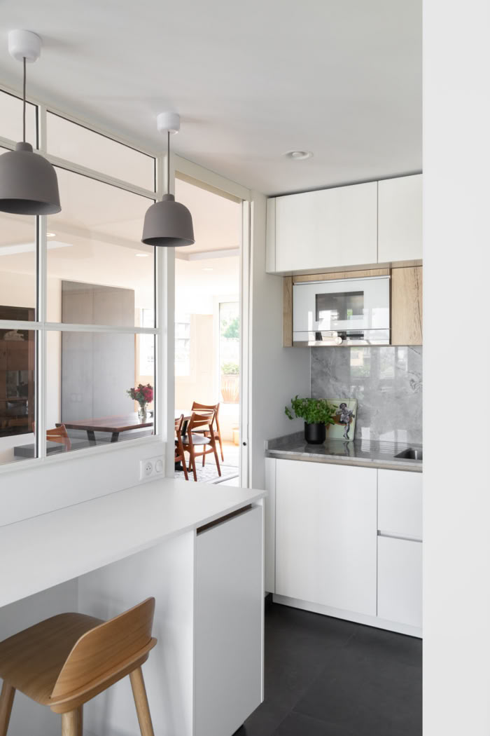 Conception d'une cuisine ouverte avec bar et verrière sur mesure pour maximiser la lumière traversante.