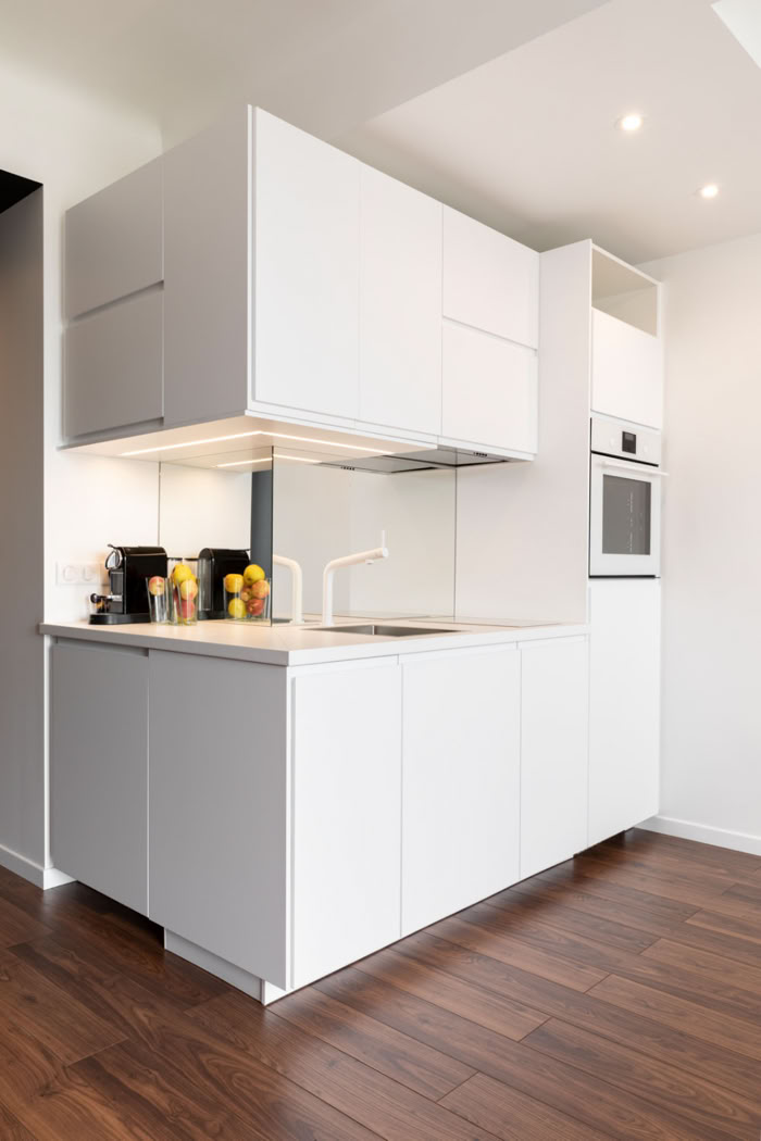 Cuisine minimaliste blanche avec crédence miroir, conception sur-mesure par votre architecte à Metz.