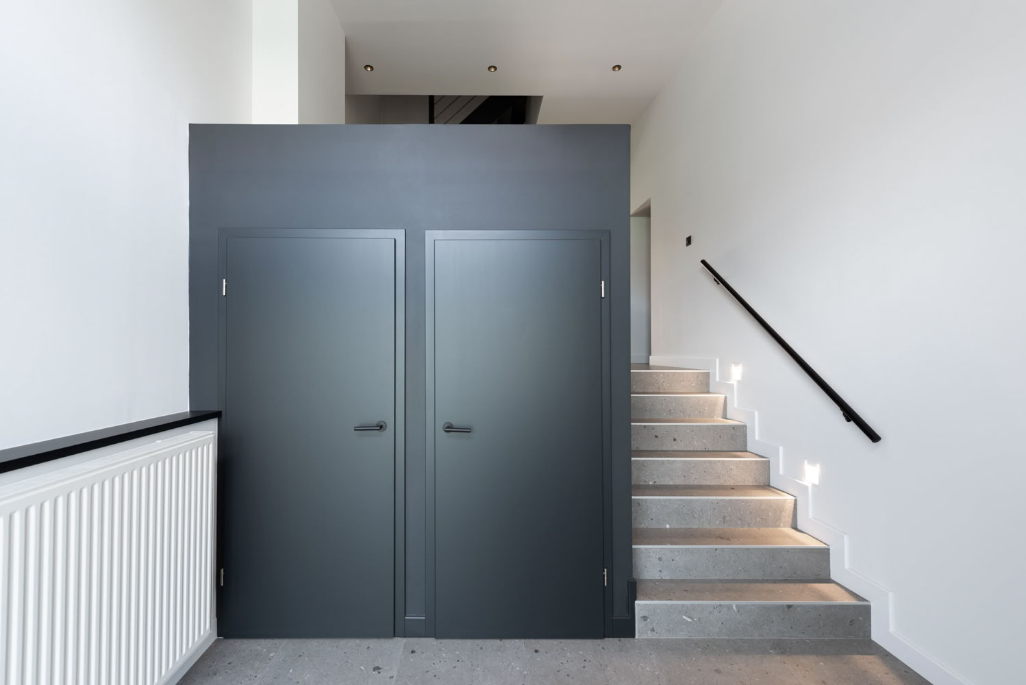 Cube noir mat abritant les penderies à l'entrée de la résidence, agencement architectural à Thionville, par Guillaume Steffanus, architecte d’intérieur.