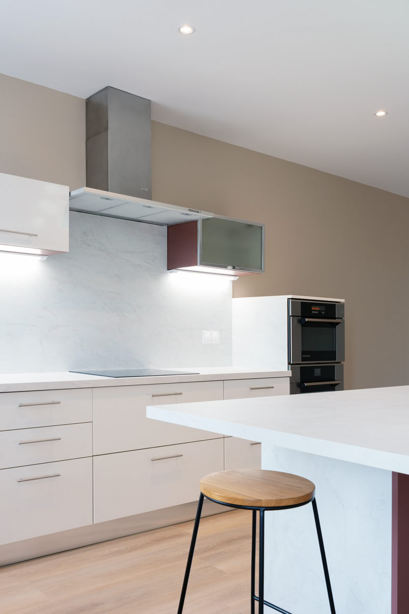 Détail d'une cuisine équipée blanche avec hotte en inox et rangements optimisés en Moselle.