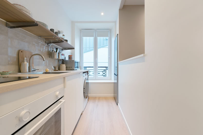 Cuisine en enfilade blanche avec plan de travail bois, agencement pour petit appartement.