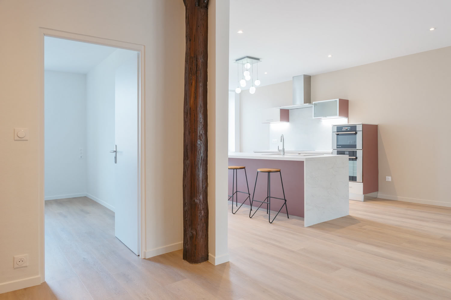 Vue d'ensemble d'une cuisine contemporaine blanche avec îlot, projet de rénovation à Metz.