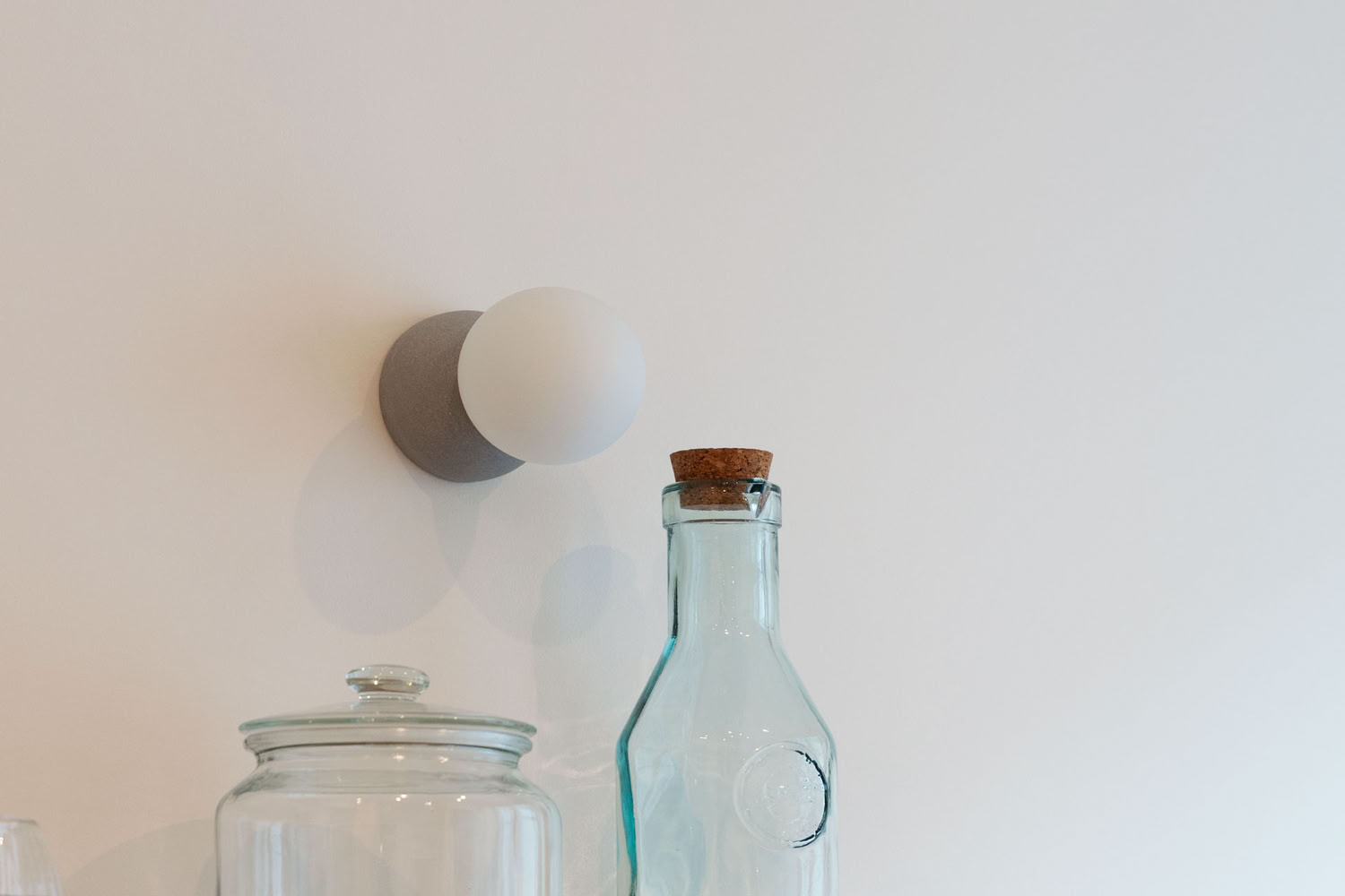 Détail d'une applique murale design et accessoires de décoration sur une étagère de cuisine.