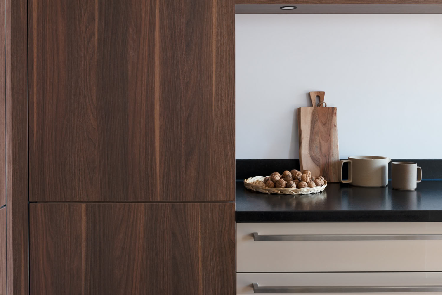 Gros plan sur finitions mobilier en noyer et plan de travail en granit noir, matériaux nobles décoration Moselle.