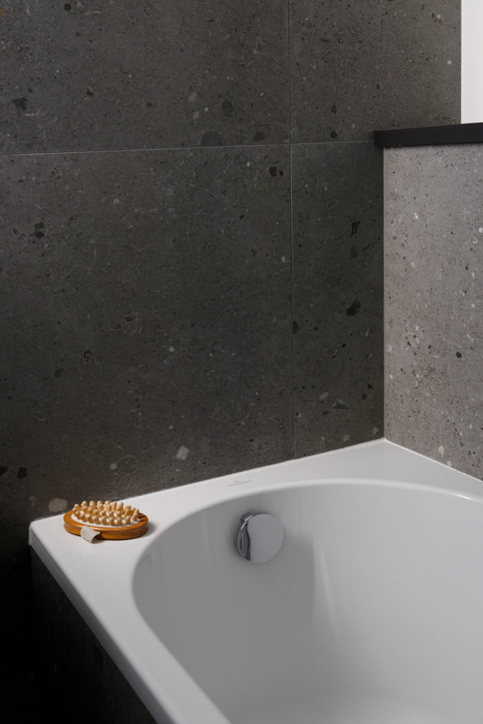 Détail baignoire blanche et revêtement carrelage gris, ambiance feutrée et pureté des lignes en Moselle.