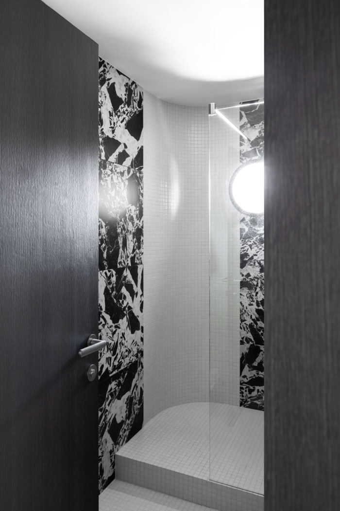 Douche personnalisée avec un hublot sur mesure offrant une vue sur la terrasse tout en préservant l'intimité.
