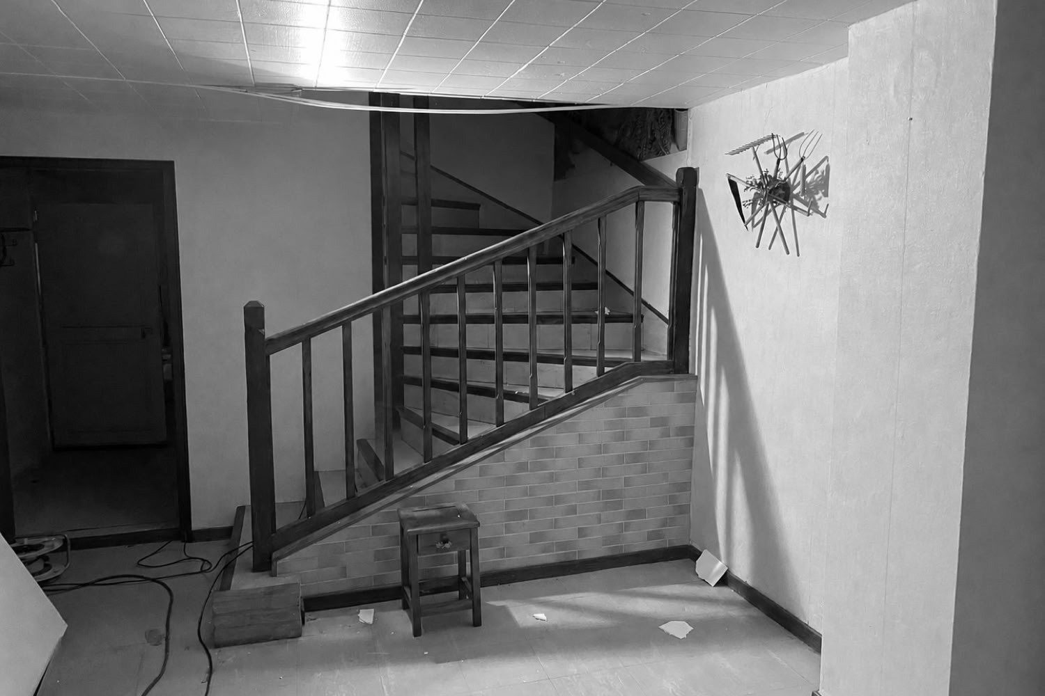Entrée d'une maison de village lorraine avant rénovation avec escalier bois et papier peint daté à Metz.