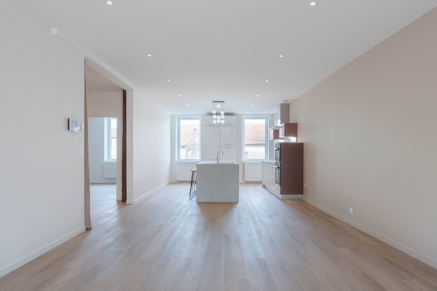 Grand séjour traversant rénové avec parquet clair et cuisine ouverte, architecte d'intérieur Metz.