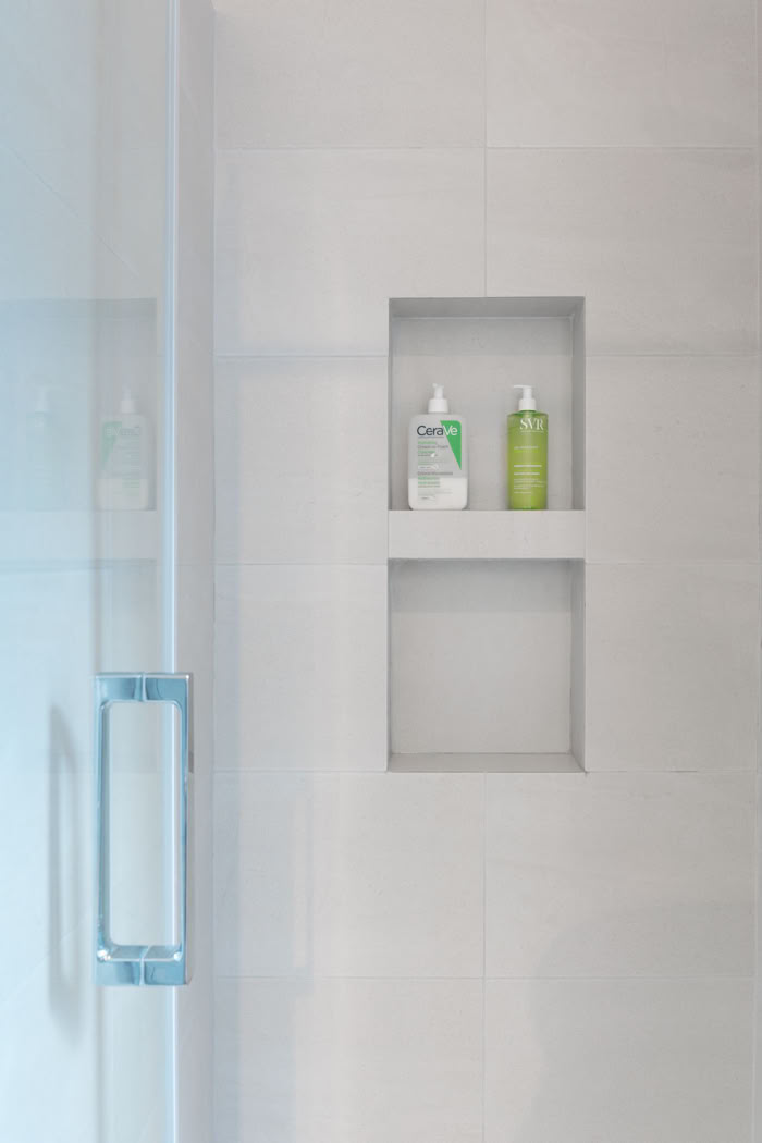 Détail de niches de rangement intégrées dans le carrelage de la douche, travail de précision.