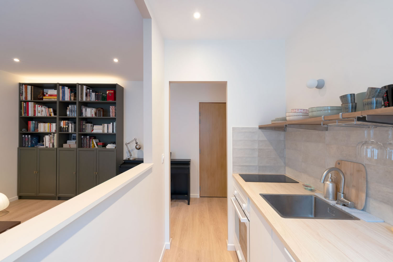 Vue depuis la cuisine vers le séjour montrant la circulation fluide et la paroi semi-ouverte.