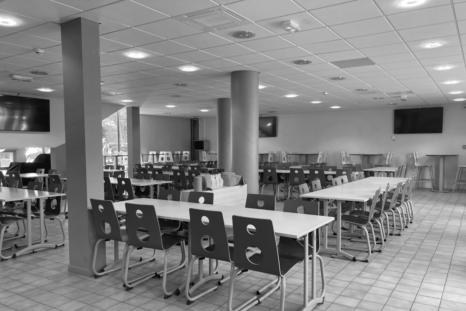 Autre perspective de la salle à manger existante, avec focus sur la rangée de tables et l'éclairage.