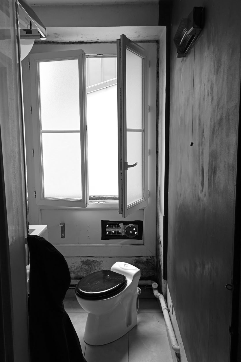 Salle de douche avant rénovation complète : équipements obsolètes et manque de luminosité.