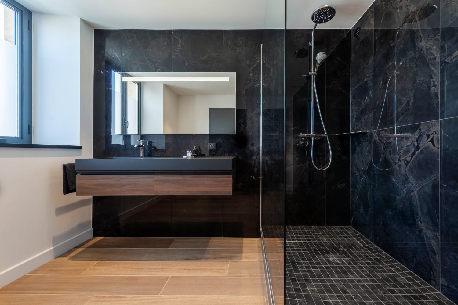 Salle de douche moderne avec carrelage imitation marbre noir et meuble vasque bois, rénovation salle d'eau Thionville.