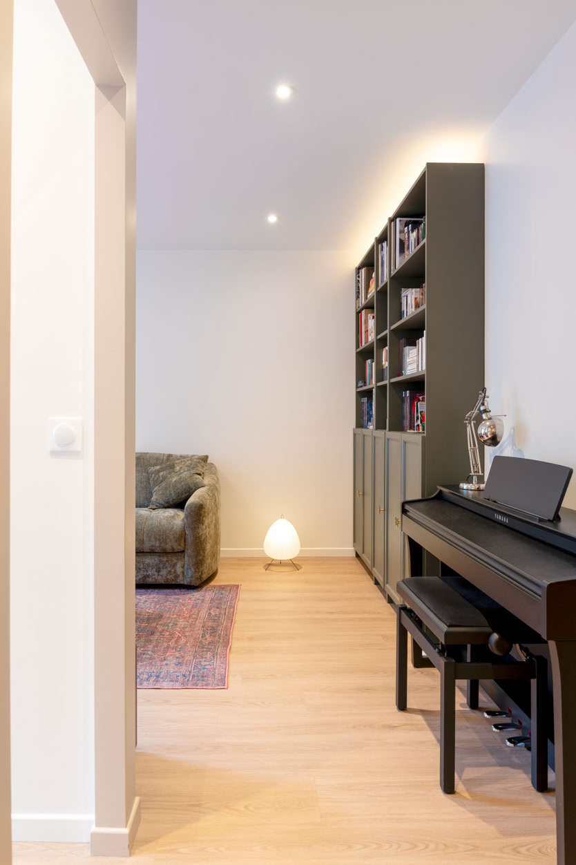 Coin salon avec piano droit et bibliothèque sur mesure grise, décoration minimaliste en Moselle.